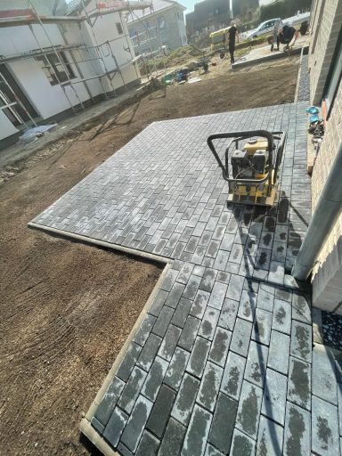 Gepflasterte Fläche im Bau, mit einem Verdichtungsgerät in der Mitte.